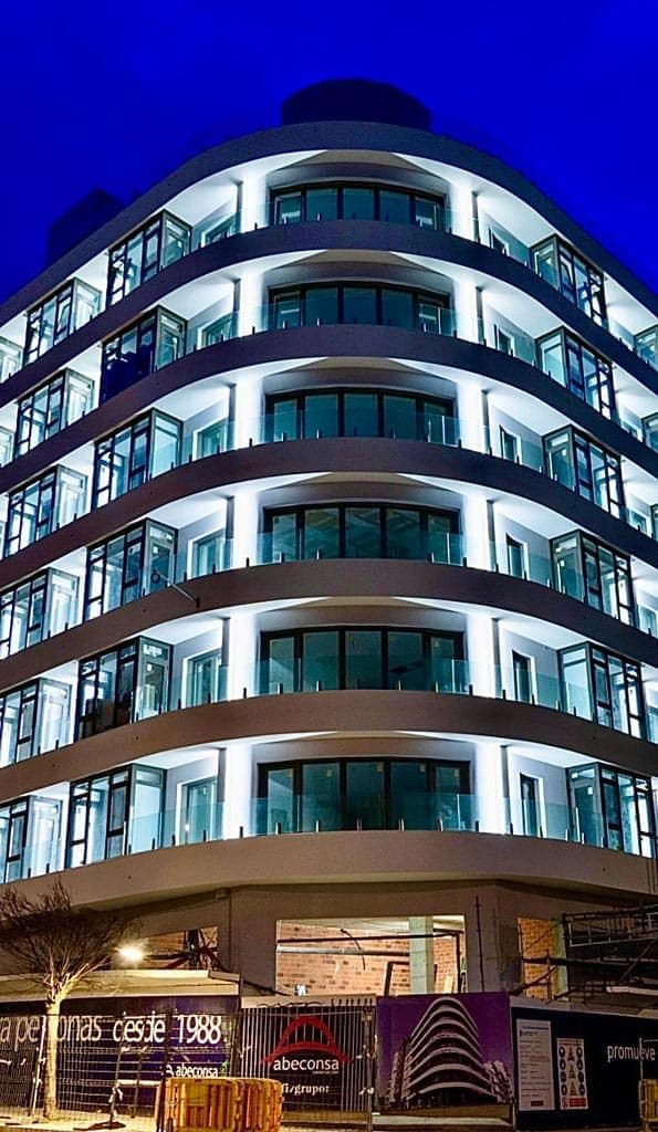 Edificio iluminado de noche con barandillas de vidrio instaladas por Nova Cristalería en A Coruña